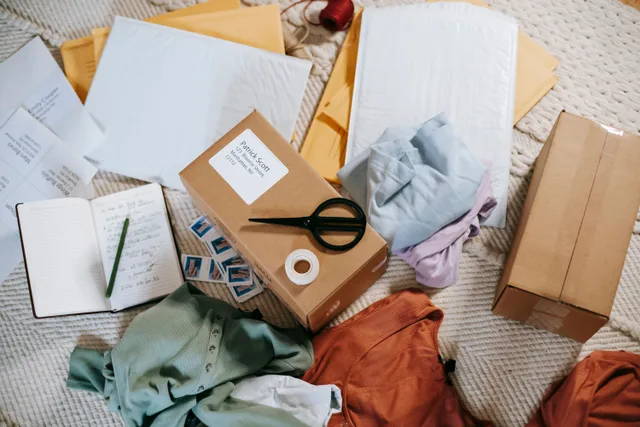 From above of various carton boxes and labels near clothes on surface in room. State sales tax on stream merch and subscriptions, a California and Texas overview
