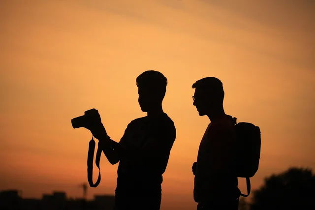 men, silhouettes, camera, photographer, sky, sunset, outdoors, vacation, nature, photography, orange sky, people, taking pictures, tourists, travellers. Does a US Livestream Host Need Business Insurance? What Triggers Coverage